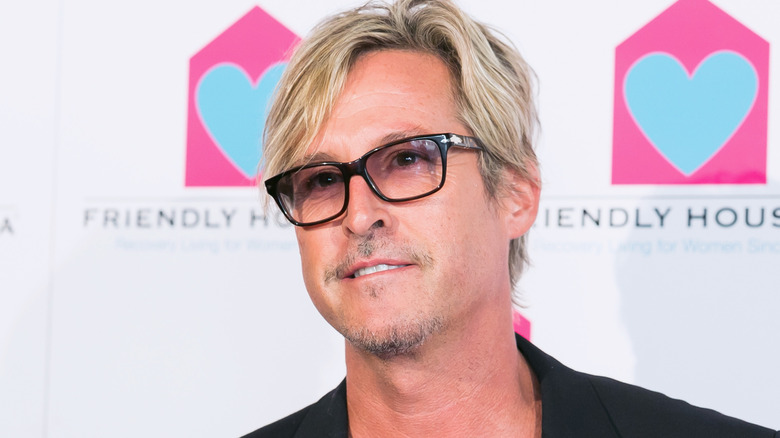 Charlie Colin smirking in glasses looking off