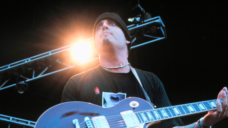 Wayne Swinny staring out on stage holding guitar