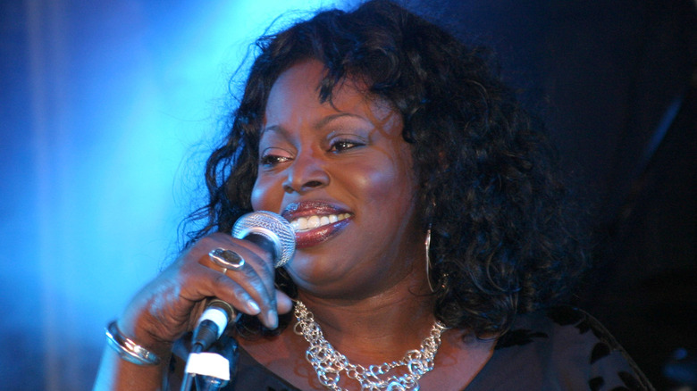 Angie Stone smiling while holding mic on stage