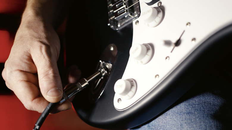 A cable plugging into an electric guitar