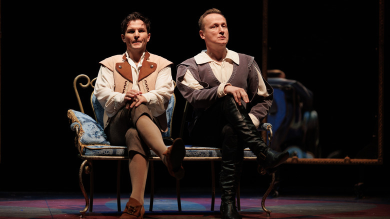 Two men in old clothes sitting on a bench on a stage during a play