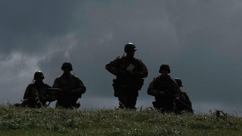 Screenshot of actors in WWII U.S. uniforms cresting hill, Saving Private Ryan