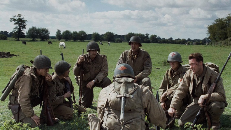 Cast members kneeling in circle in field, Saving Private Ryan