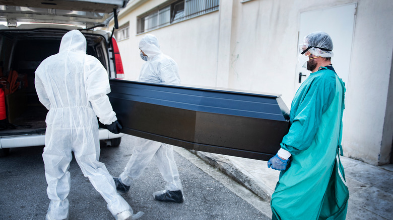 Men in protective gear carry coffin