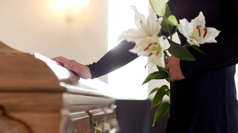 Woman with hand on coffin