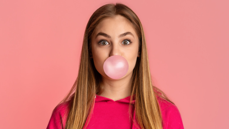 girl blowing bubble from chewing gum