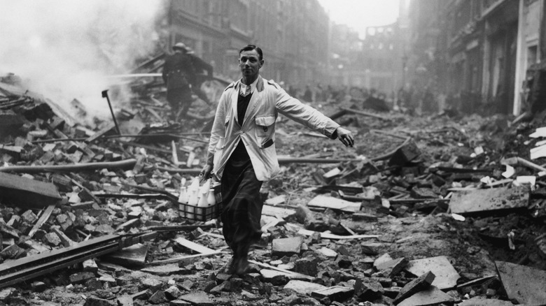 man delivering milk through destroyed street london blitz
