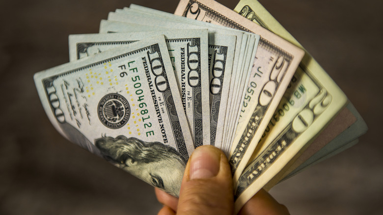 hand holding various denominations of cash