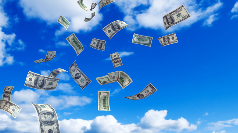 Paper currency flying through blue sky