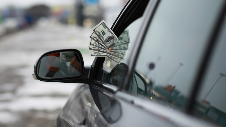 money sticking out of a car window