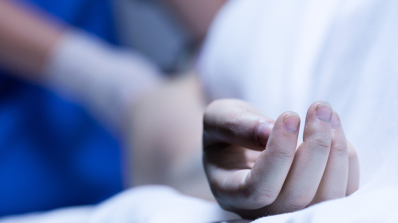 Hand resting on white sheet