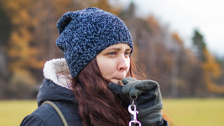 woman with hand blowing dog whistle