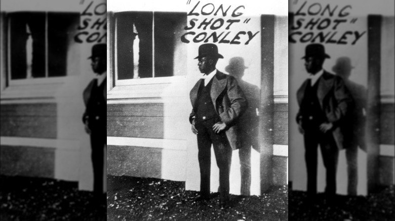 Jess 'Long Shot' Conley stood in suit and bowler hat