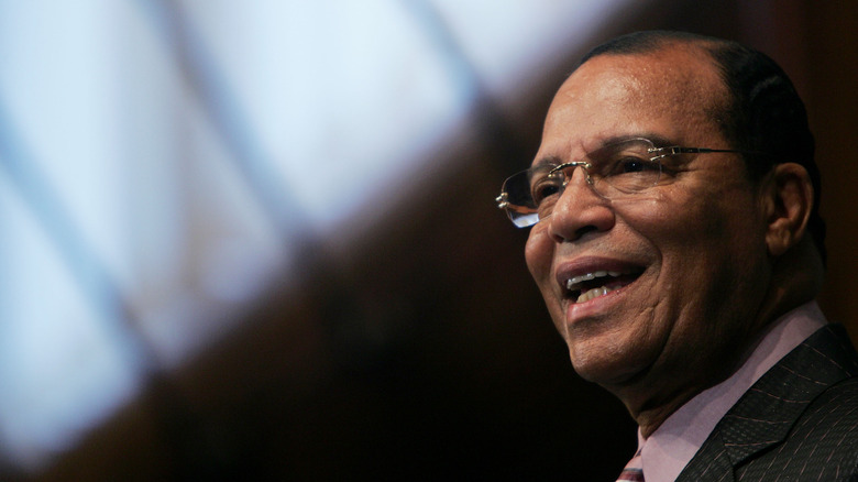 Louis Farrakhan smiling suit and glasses plain background