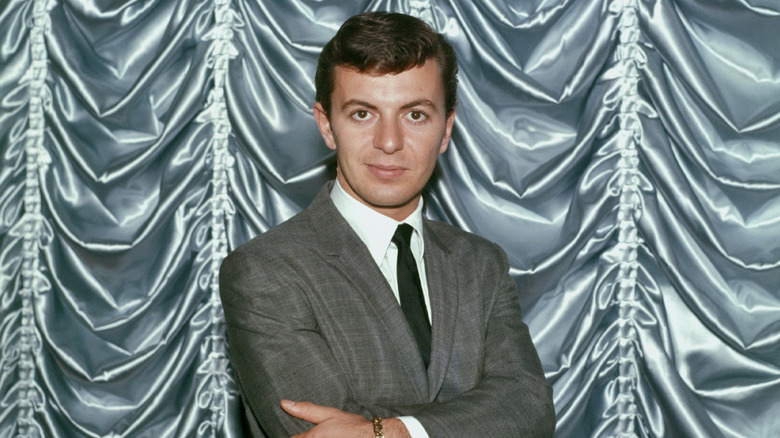 Dion DiMucci of Dion and the Belmonts posing in front of a silver curtain.
