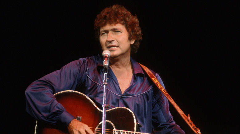 Mac Davis singing and playing guitar