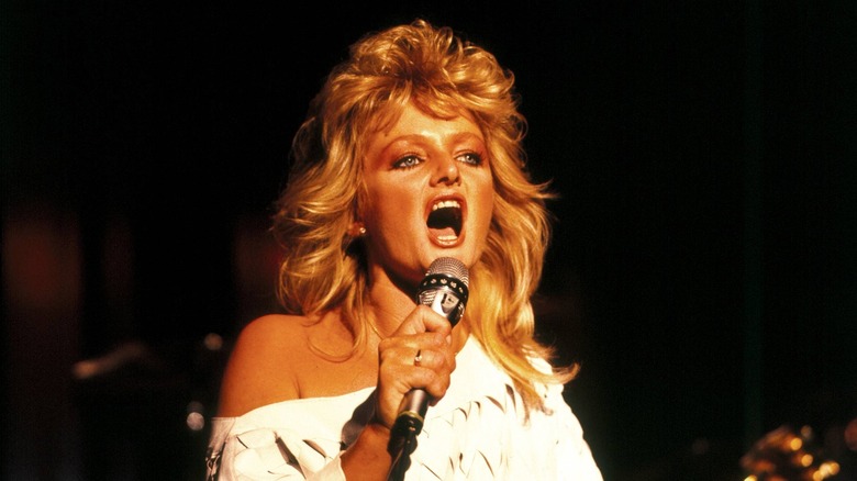 Bonnie Tyler singing into microphone onstage in 1984