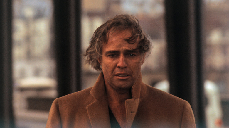 Marlon Brando with long hair, wearing a tan-colored coat