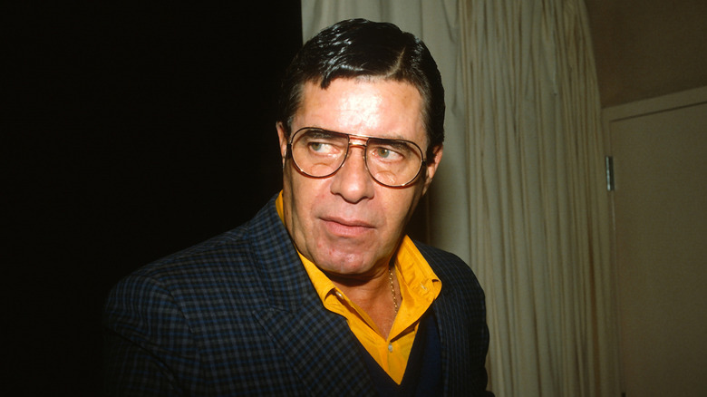 Jerry Lewis wearing glasses, with a curtain in the background