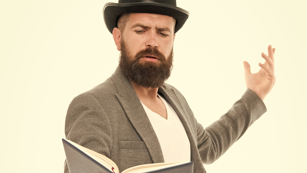 A man acts out something he's reading in a book