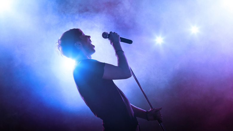 Man singing at microphone with galaxy-themed lights surrounding him