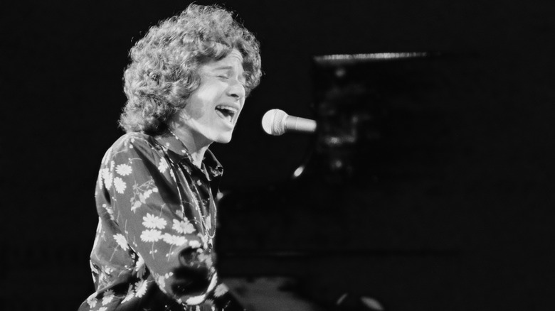 Carole King singing and playing piano on stage