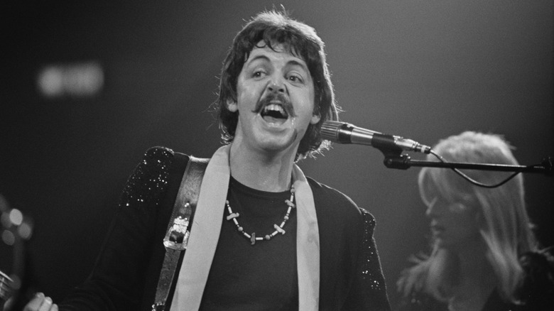 Paul McCartney singing on stage while holding guitar