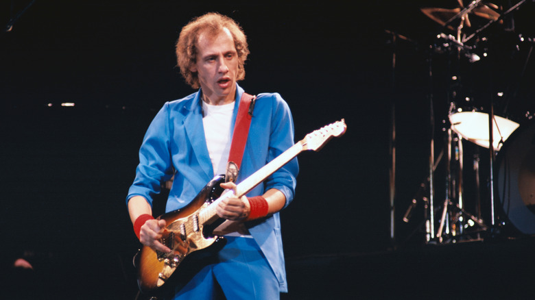 Mark Knopfler onstage in blue suit with guitar