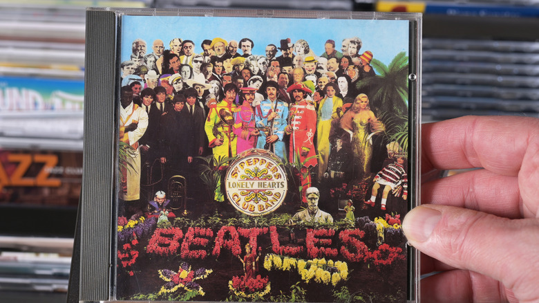 hand holding Sgt. Pepper's Lonely Hearts Club Band CD