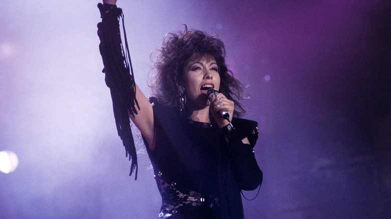 Jennifer Rush singing on stage in black dress with arm aloft