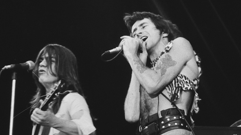 Bon Scott singing into microphone with Malcolm Young accompanying