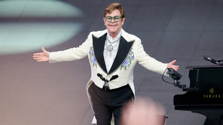 Elton John performing on stage with arms wide open