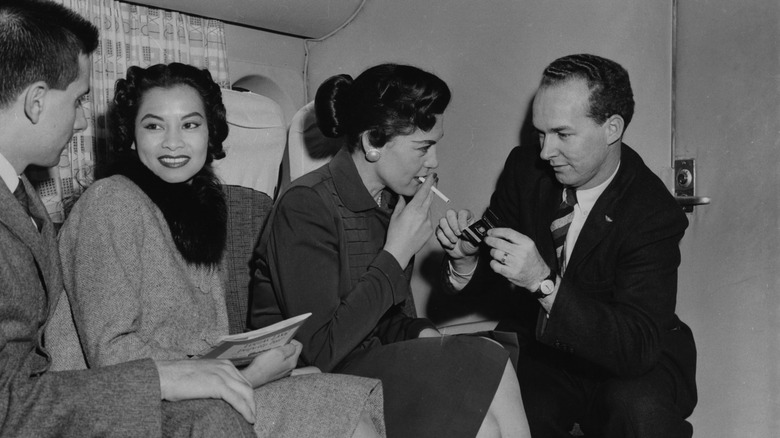 Man lights woman's cigarette on a plane 1950s