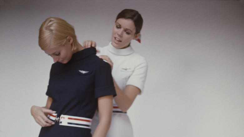 two flight attendants adjusting their uniforms