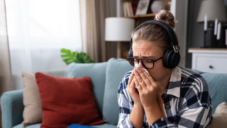 young woman on sofa wearing headphones and crying