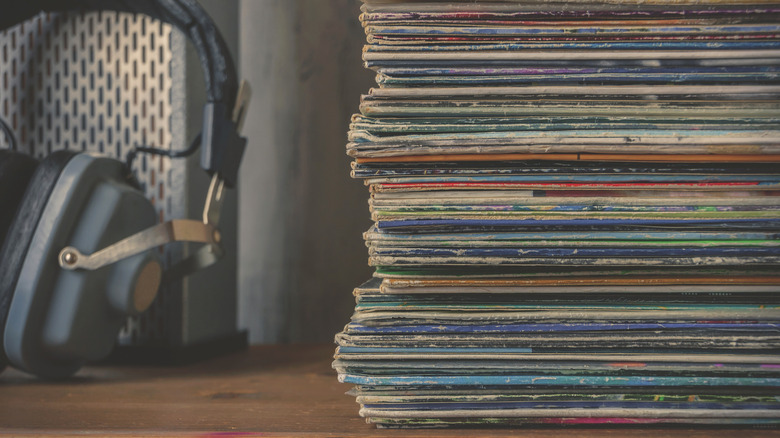 stack of old vinyls beside a pair of headphones
