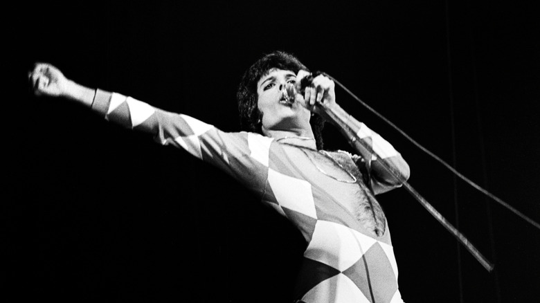 Freddie Mercury singing into microphone with arm out