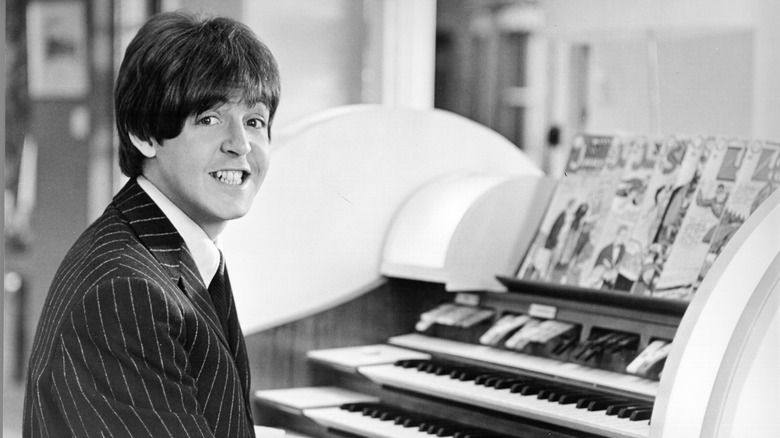 Paul McCartney smiling sat at piano