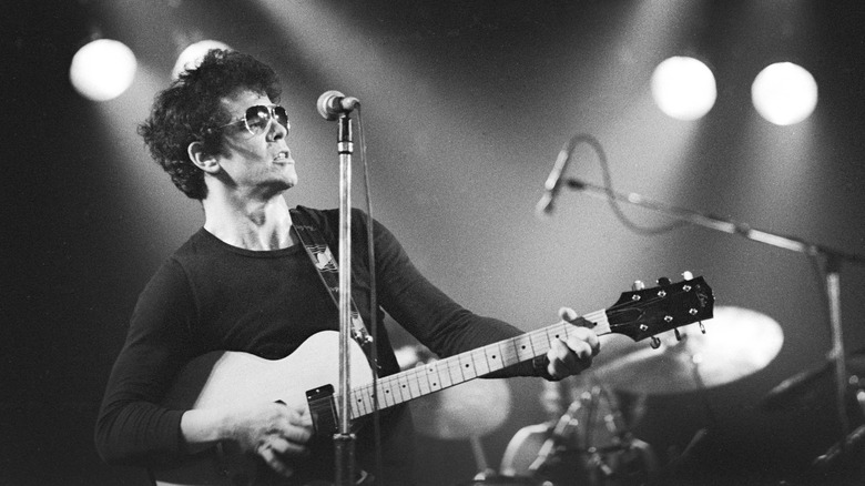 Lou Reed playing guitar on stage in sunglasses