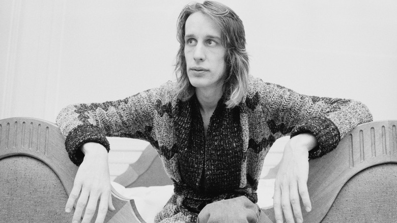 Todd Rundgren sitting down while having his picture taken.