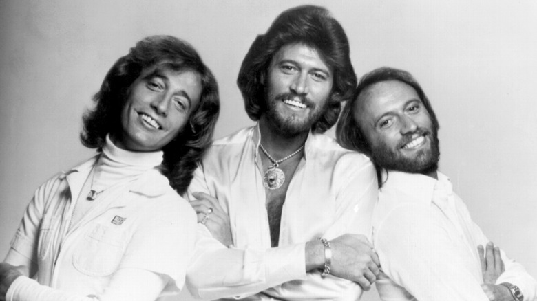 The Bee Gees standing together in white suits