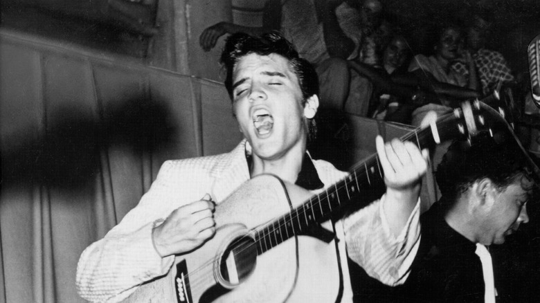 Elvis Presley giving an impassioned performance with acoustic guitar