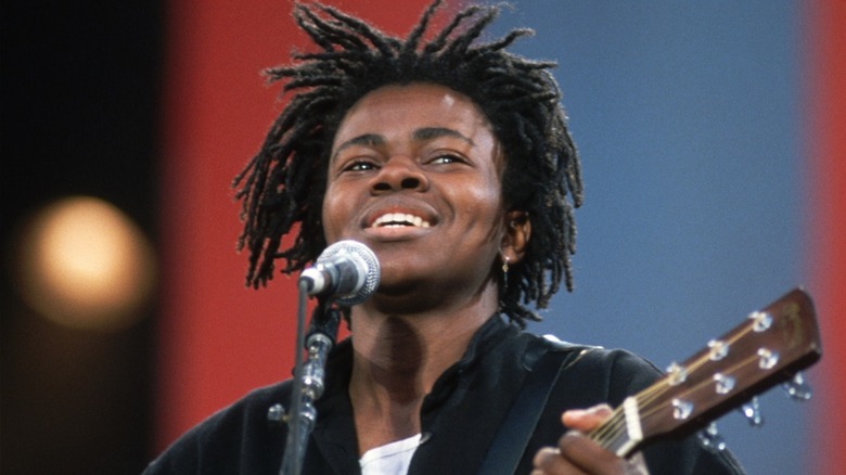 Tracy Chapman performing on stage with a guitar