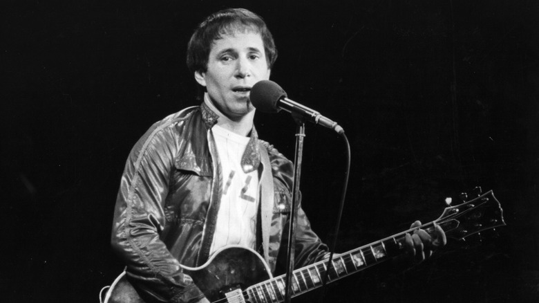 Paul SImon plays guitar and sings live