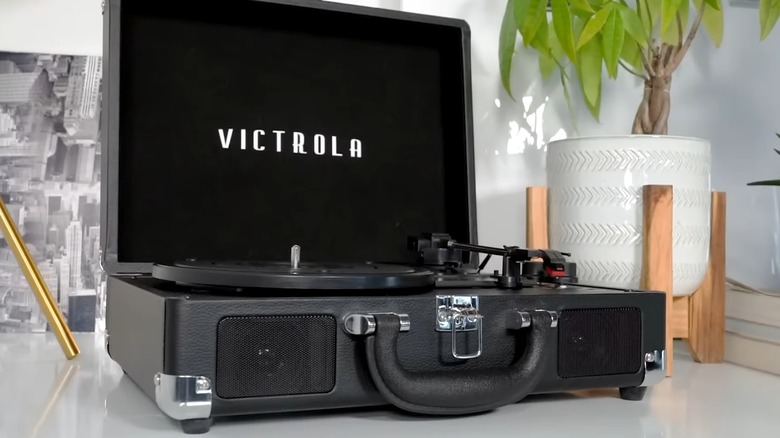 Black Victrola Journey+ portable vinyl player on table by plant