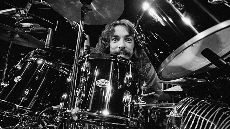 Neil Peart peering through drum kit