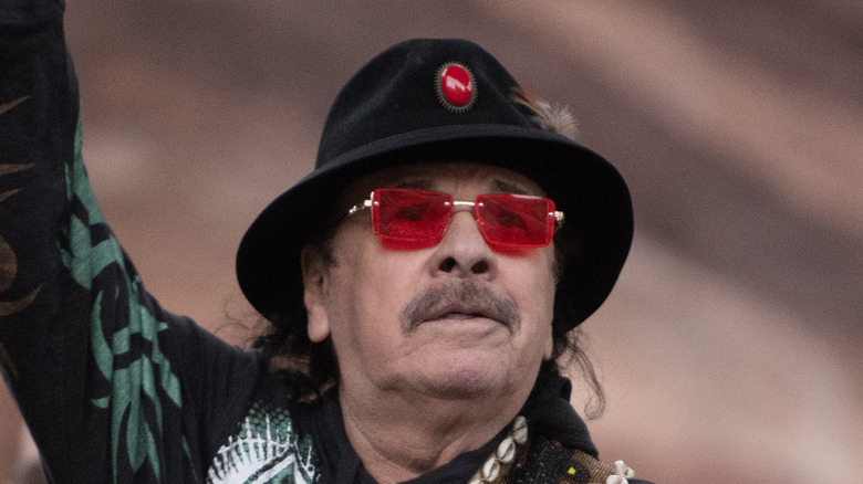 Carlos Santana on stage looking into crowd with arm raised