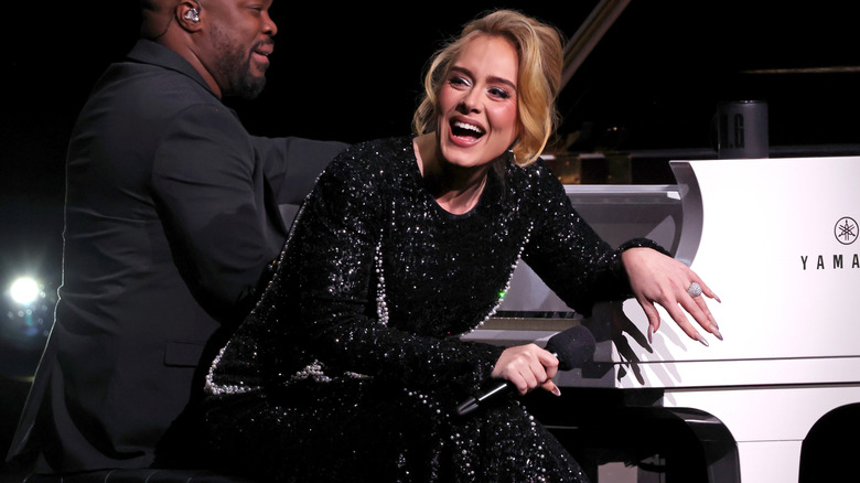 Adele sitting at piano with mic