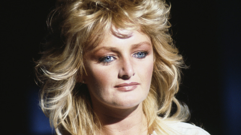 Bonnie Tyler with a serious expression on her face amid a black background
