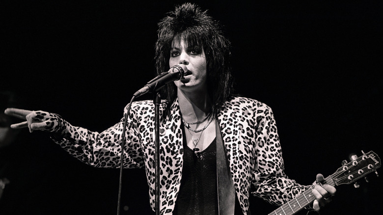 Joan Jett playing guitar on stage in leopard print jacket